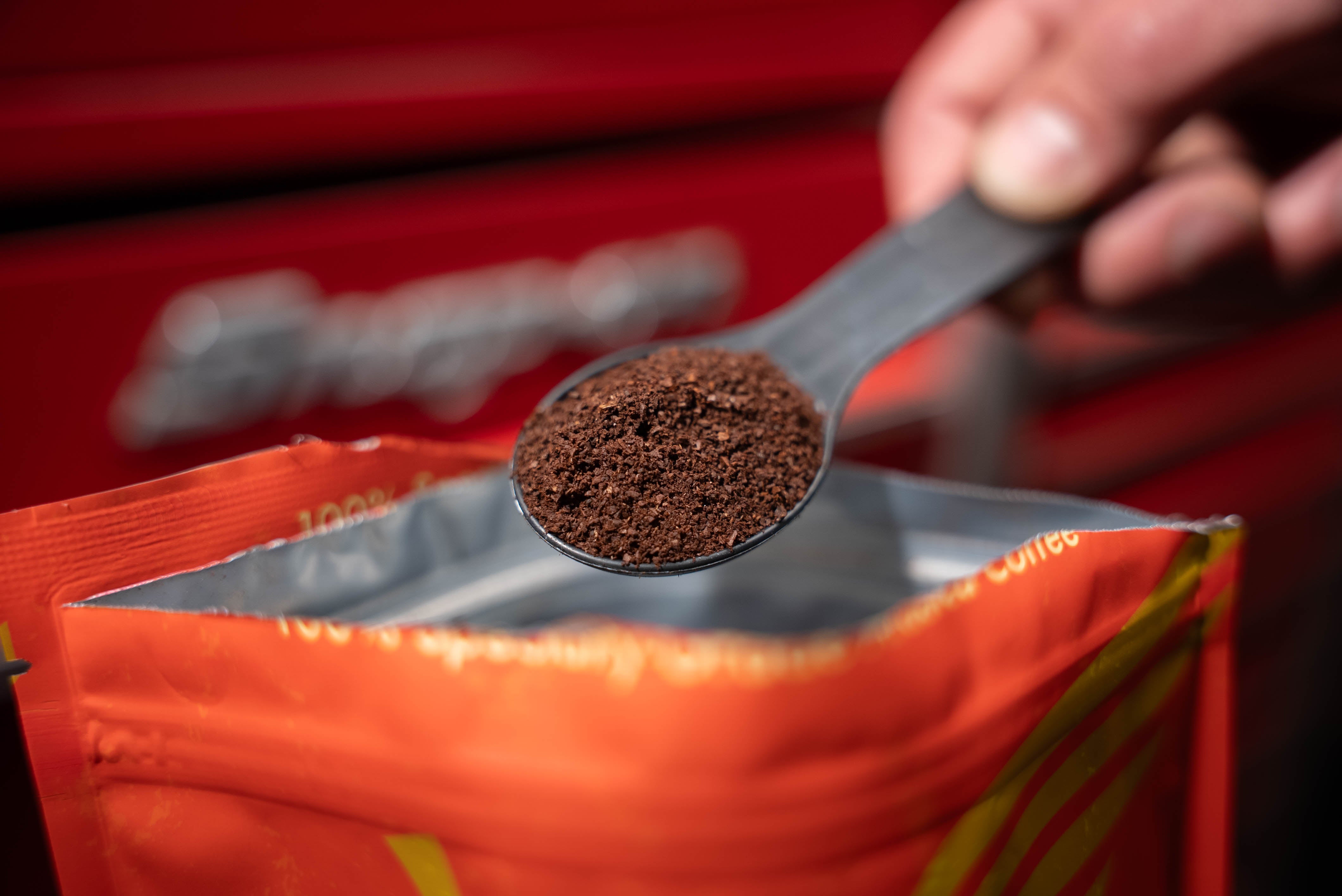 Spoonful of coffee over an open red coffee packet with a snap on tool box in the background.