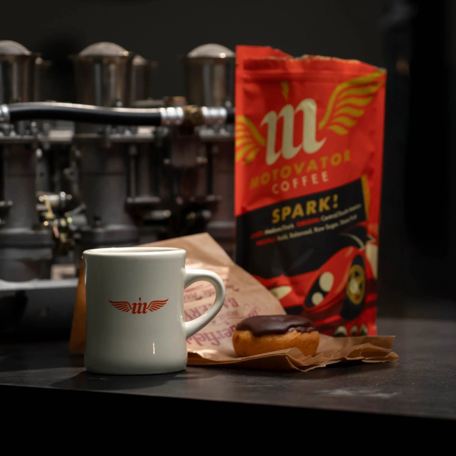Mug and coffee and donut bag on a counter with weber careurator intake in the background