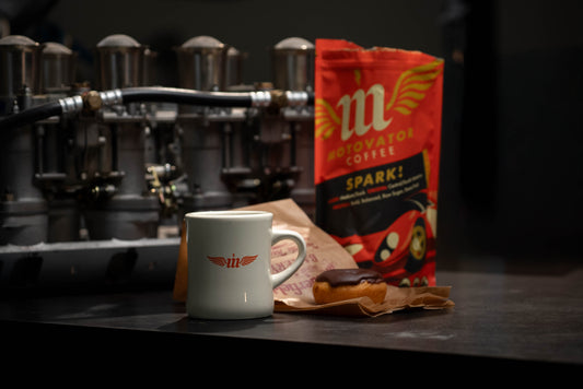 Mug and coffee and donut bag on a counter with weber careurator intake in the background