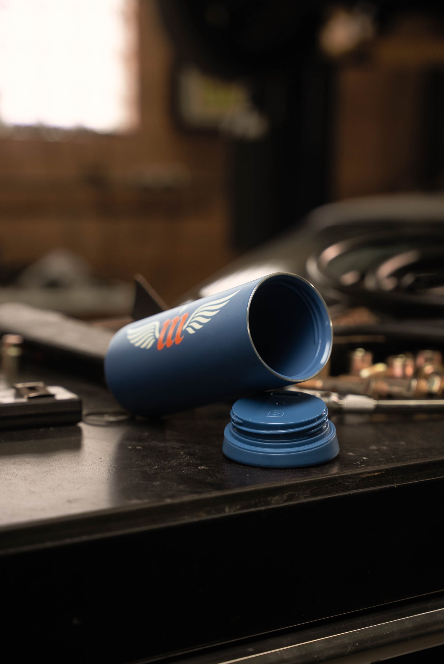 Blue Motovator travel mug on a tool chest with lid off showing color matched ceramic inside