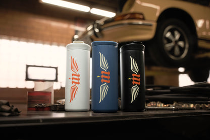 Three tumblers with a logo on a workbench in a garage setting