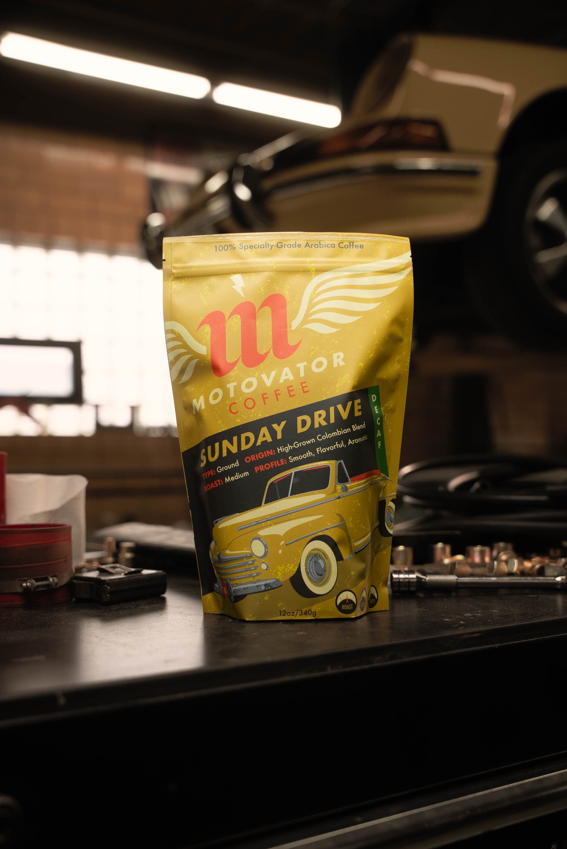 Motovator decaf coffee bag on a workbench in a workshop near a porsche