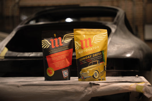 Motovator decaf coffee bag Front and back sitting on a table by a Porsche 911 at a restoration shop