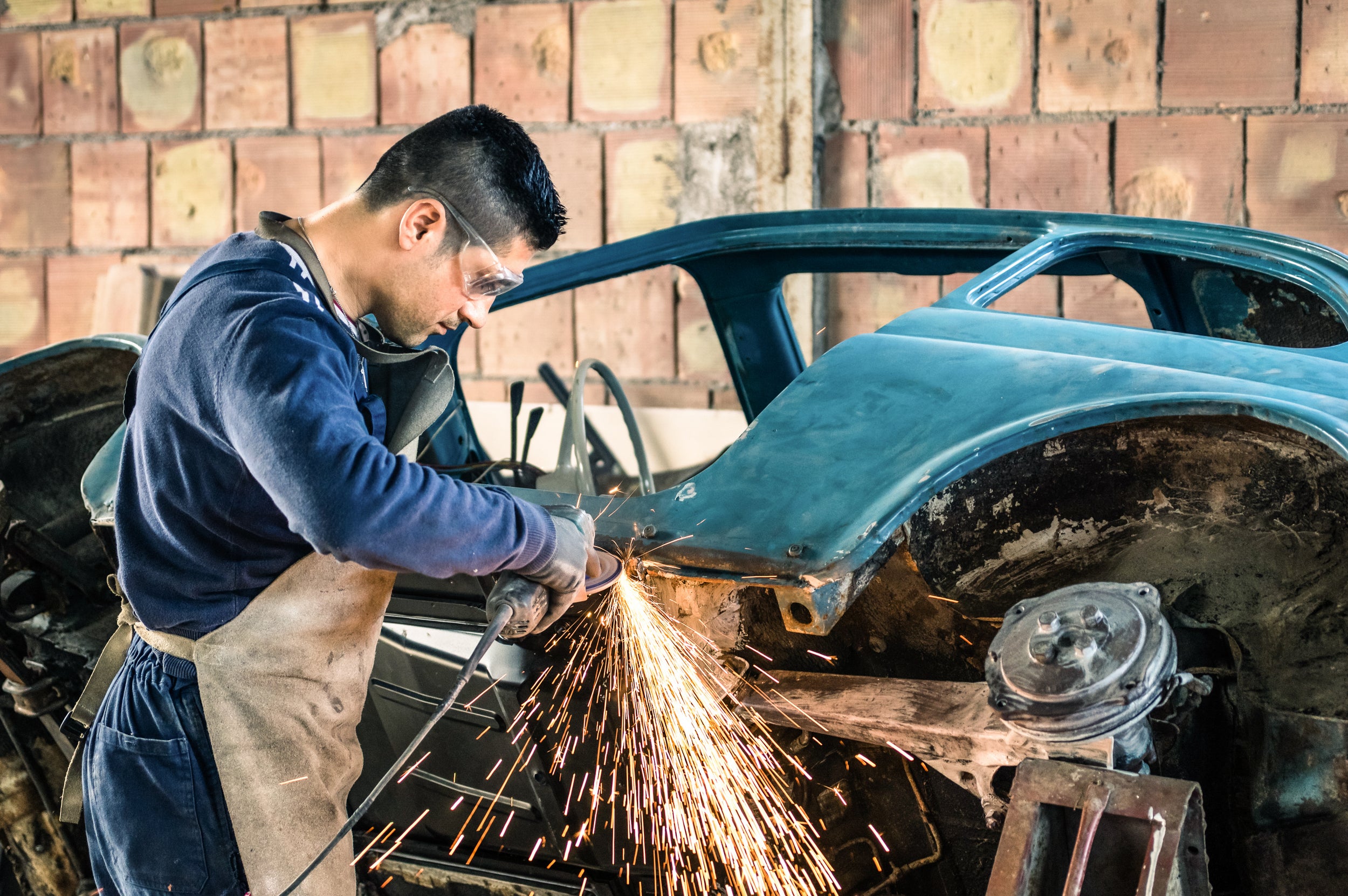 young man grinding on a car and throwing sparks